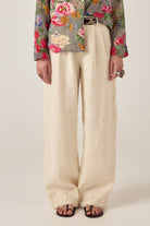 Model wearing ELSHAM BOUTIQUE ivory cotton-linen Otto pants with front pleats and embroidered hem details