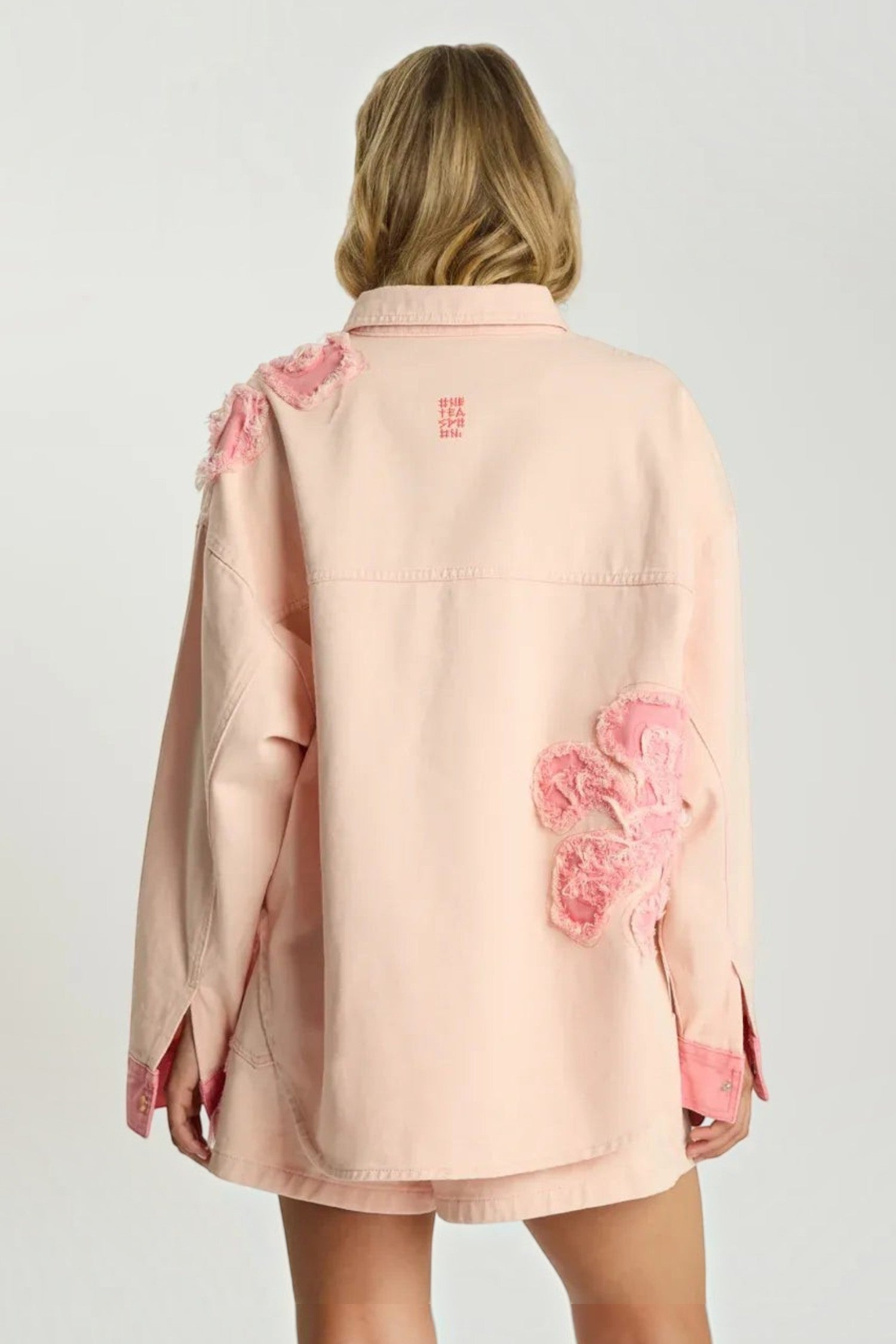 Back view of ELSHAM BOUTIQUE pink petal oversized denim shacket with frayed floral applique details on 100% cotton