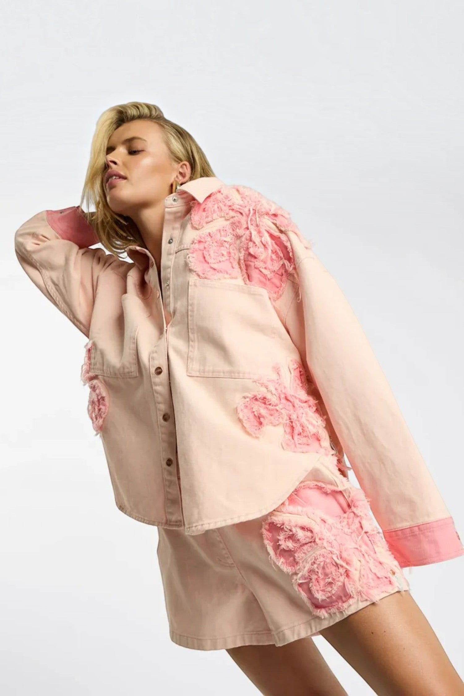Model wearing ELSHAM BOUTIQUE pink petal oversized cotton denim shacket with frayed edge detailing and button front