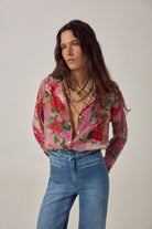 ELSHAM BOUTIQUE Piti shirt in rouge cotton with floral print over stripes, worn by a model with a shell necklace.