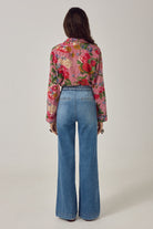 Back view of ELSHAM BOUTIQUE Piti shirt in rouge floral print over stripes, worn tucked into blue wide-leg jeans.