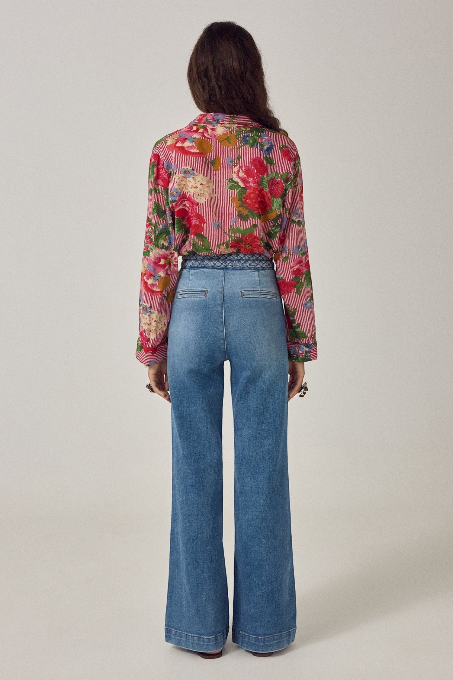 Back view of ELSHAM BOUTIQUE Piti shirt in rouge floral print over stripes, worn tucked into blue wide-leg jeans.