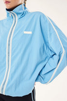 ELSHAM BOUTIQUE Radius Jacket in Alaskan Blue featuring a funnel neck, zip front, and white side stripe detail.