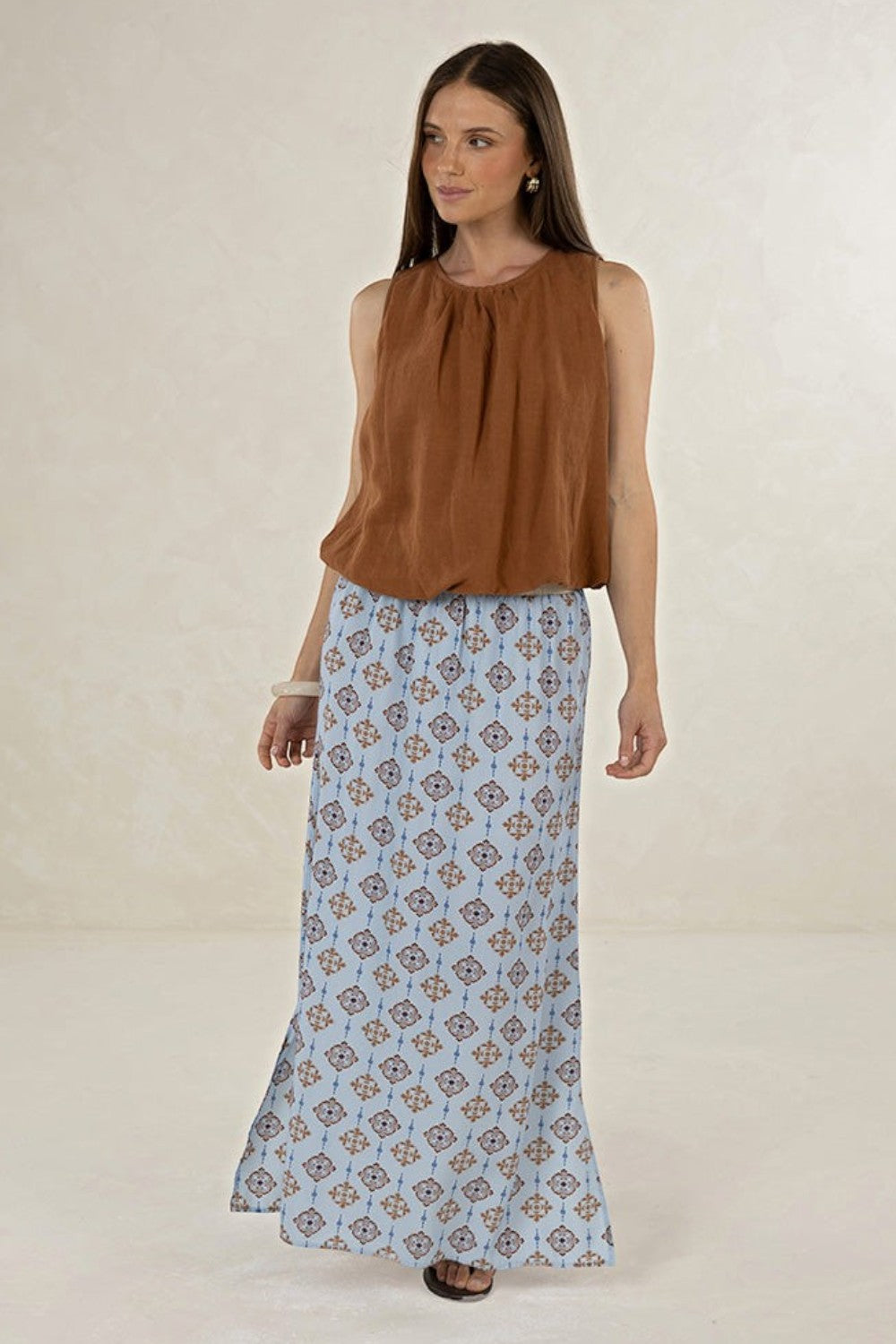 Model wearing ELSHAM BOUTIQUE tobacco brown linen-tencel sleeveless Samara Top with a patterned blue maxi skirt