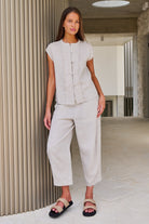 Model wearing ELSHAM BOUTIQUE sand linen cropped tapered pants with an elasticated waistband and side pockets.