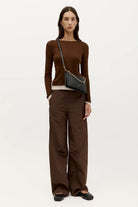 Model wearing a black ELSHAM BOUTIQUE Siamese Bag in calf nappa leather with a gold chain strap as a crossbody bag.