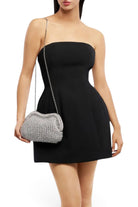 Model wearing an ELSHAM BOUTIQUE silver metallic crochet clutch bag with a shoulder chain and black strapless dress.