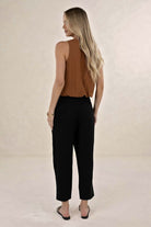 Model wearing ELSHAM BOUTIQUE tobacco linen-tencel sleeveless Samara Top with black trousers, back view