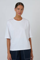Model wearing an ELSHAM BOUTIQUE white cotton crew neck top with a relaxed boxy fit and elbow-length drop sleeves.