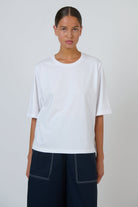 Model wearing an ELSHAM BOUTIQUE white cotton crew neck top with a relaxed boxy fit and elbow-length drop sleeves.