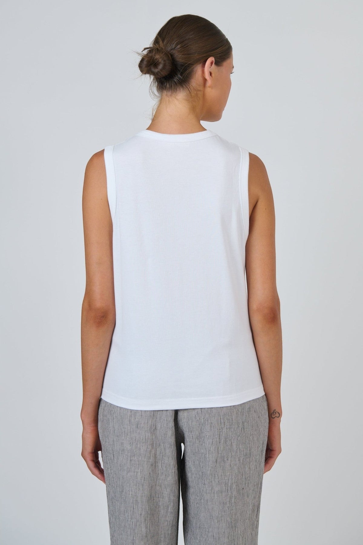 Back view of ELSHAM BOUTIQUE white cotton sleeveless muscle top with a round neckline on a model