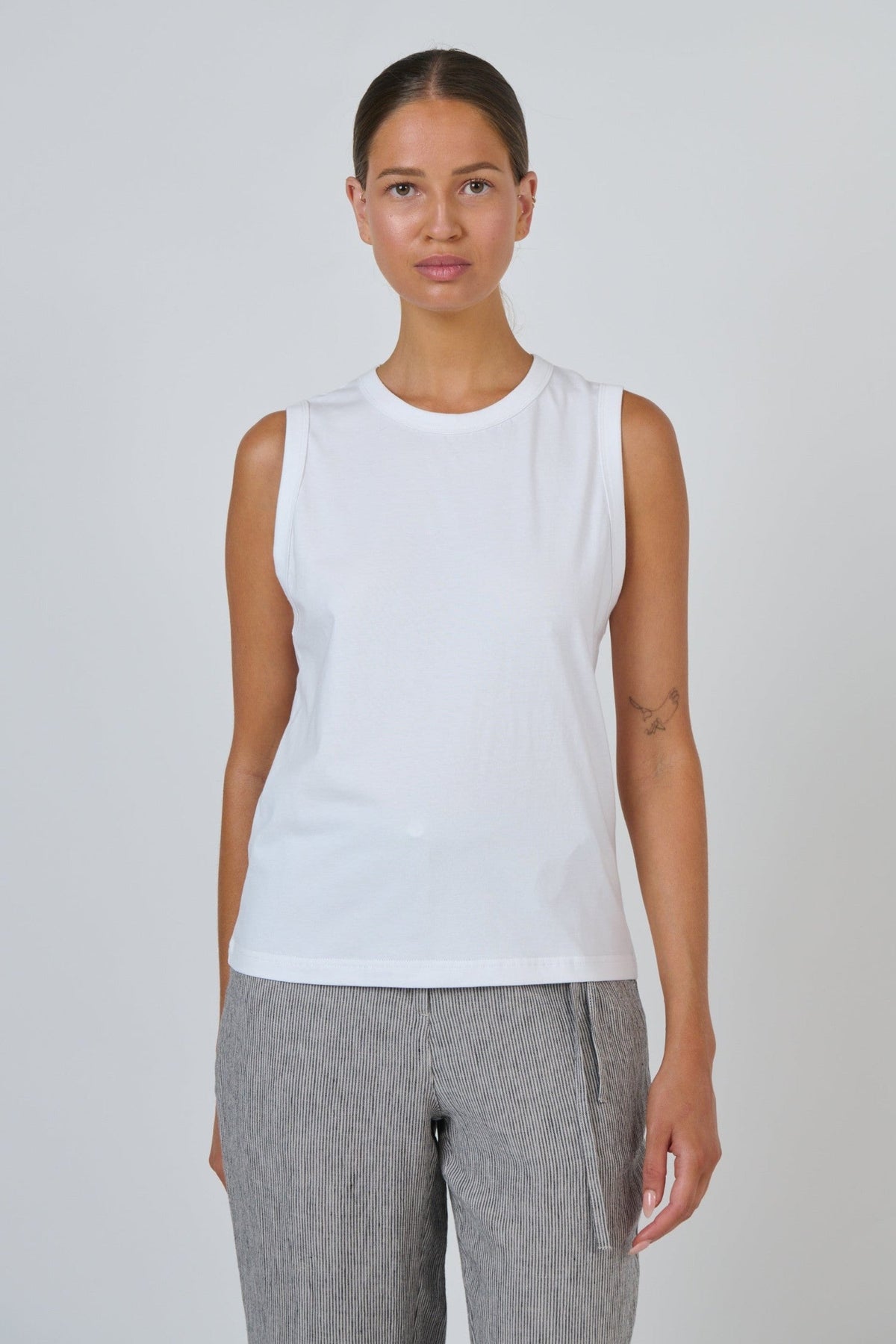 ELSHAM BOUTIQUE white cotton sleeveless muscle top with a round neckline worn by a model against a plain background