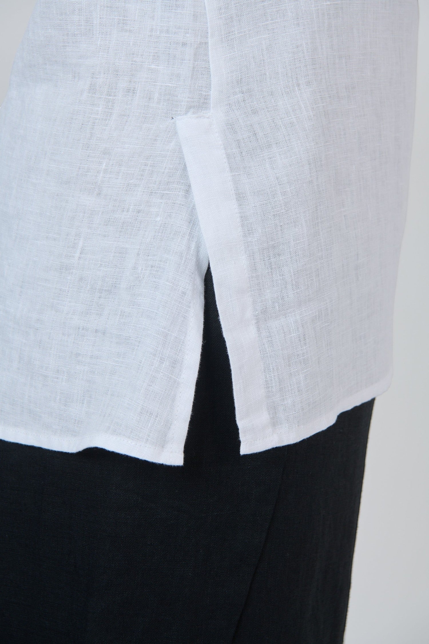 ELSHAM BOUTIQUE white linen top featuring a side hem slit detail and lightweight breathable fabric texture