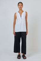 ELSHAM BOUTIQUE white sleeveless linen top with deep V-neck and contrast piping, worn with black trousers