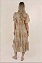 Back view of a woman wearing an ELSHAM BOUTIQUE Yasmin midi dress in almond floral print with tiered frill detailing.