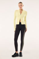 Model wearing ELSHAM BOUTIQUE soft yellow rib knit zip cardigan with high neck and split cuffs over black leggings.